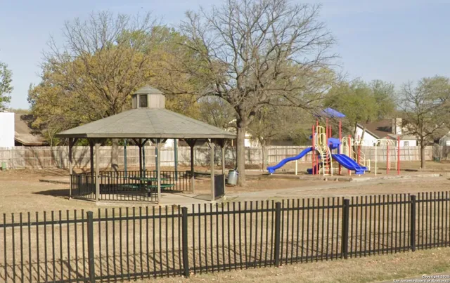 a view of a street with large trees and a houses