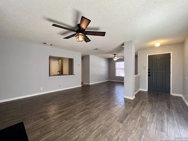 a view of empty room with wooden floor and ceiling fan