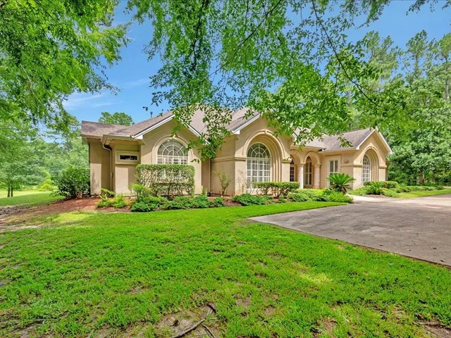 a view of a house with a yard and large trees