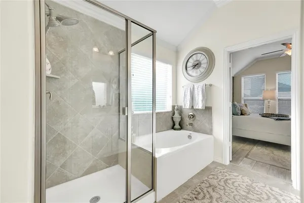 a bathroom with a bathtub a mirror a clock and a shower