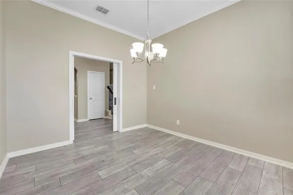 a view of a chandelier in big room with wooden floor