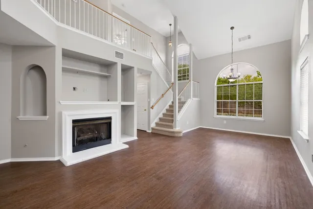 a view of an empty room with wooden floor fireplace and a window
