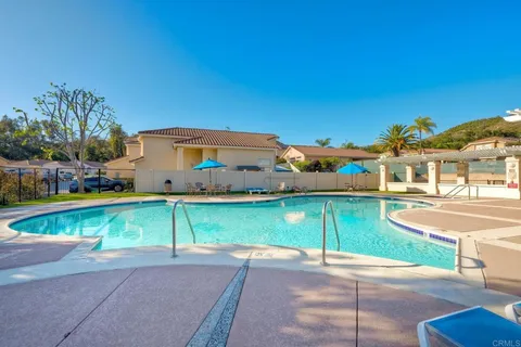 a view of a swimming pool with a lawn chairs under an umbrella