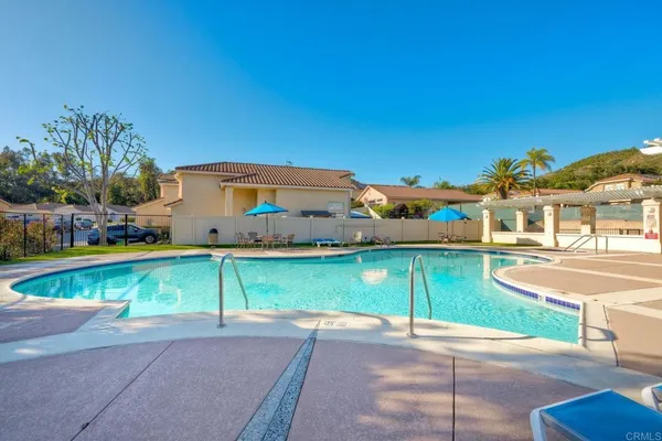 a view of a swimming pool with a lawn chairs under an umbrella