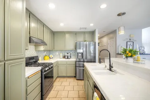 a kitchen with stainless steel appliances a sink a stove a refrigerator cabinets and a sink