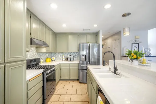 a kitchen with stainless steel appliances a sink a stove a refrigerator cabinets and a sink