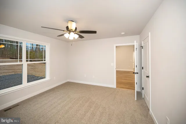 en empty room with windows and ceiling fan