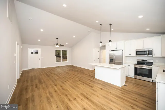 a large kitchen with stainless steel appliances kitchen island a large counter top and a wooden floors