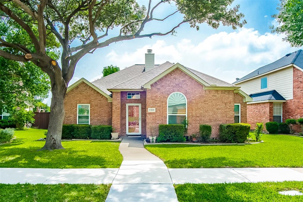 Brick exterior residence with a shingled roof, a prominent arched window, and a concrete pathway leading to the front entry