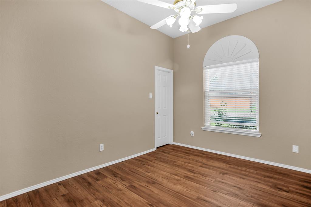 8308 Spring Ridge Drive Plano, TX 75025 - Photo 12 of 28 Vaulted ceiling room featuring a large arched window with blinds, wood-finish flooring, and a ceiling fan with integrated lighting