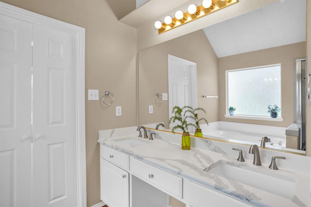 8308 Spring Ridge Drive Plano, TX 75025 - Photo 14 of 28 Dual vanity featuring a white cabinet base with integrated sinks, brushed nickel fixtures, and a marble-finish countertop