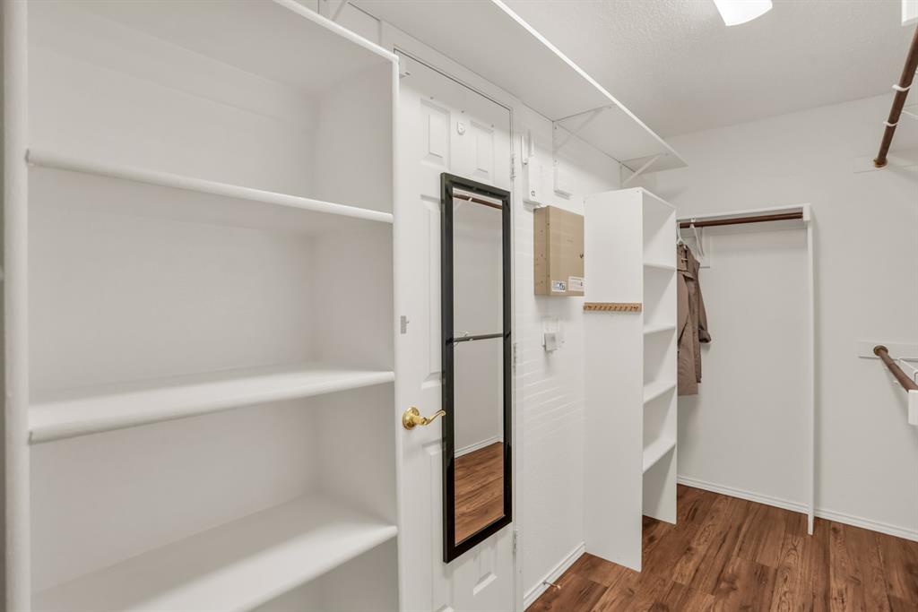 8308 Spring Ridge Drive Plano, TX 75025 - Photo 17 of 28 Walk-in closet featuring extensive white shelving, multiple hanging rods, wood-finish flooring, and a full-length mirror