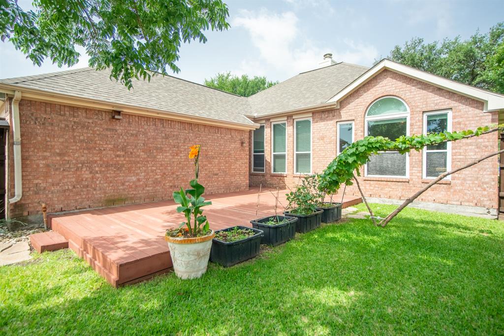 8308 Spring Ridge Drive Plano, TX 75025 - Photo 20 of 28 Expansive backyard featuring a manicured lawn, a large wooden deck with multiple steps, and a brick exterior with numerous windows