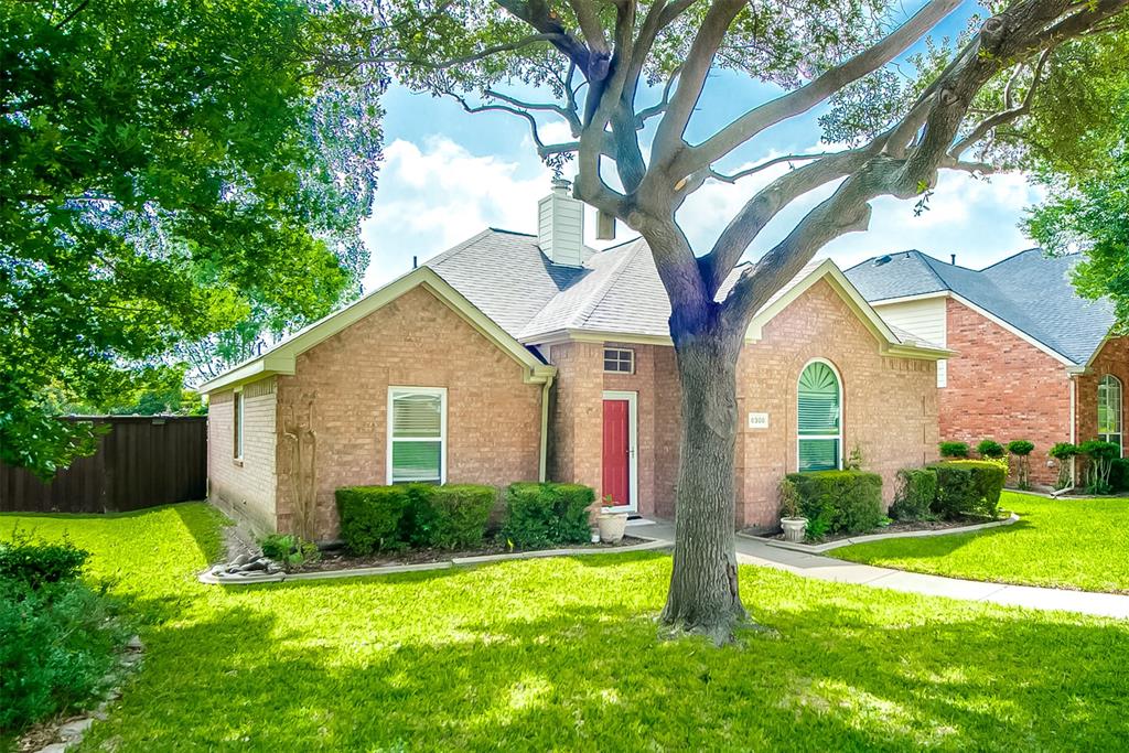 8308 Spring Ridge Drive Plano, TX 75025 - Photo 2 of 28 Brick exterior residence with a prominent mature tree, manicured lawn, and a red entry door