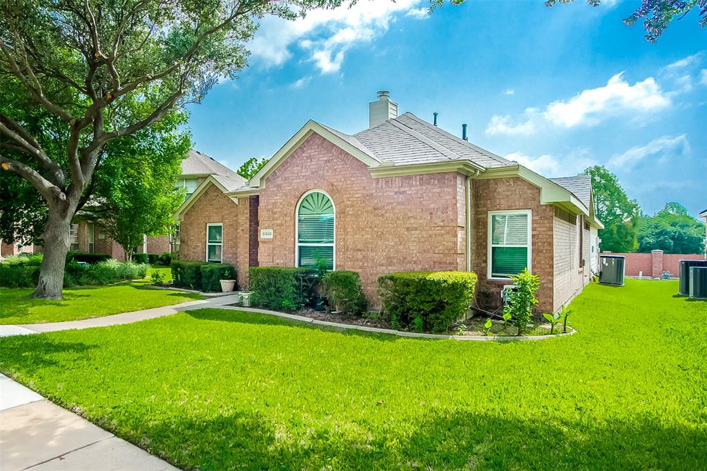 8308 Spring Ridge Drive Plano, TX 75025 - Photo 3 of 28 Brick exterior with arched window detail, mature front yard tree, established shrubbery, and a concrete walkway