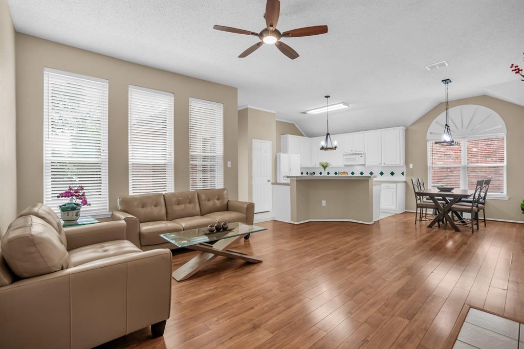 8308 Spring Ridge Drive Plano, TX 75025 - Photo 6 of 28 Open-concept living area featuring wood-finish flooring, a ceiling fan, and three vertical windows with blinds