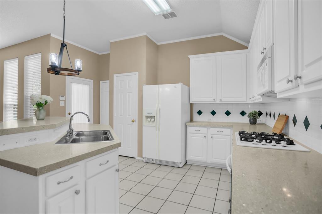 8308 Spring Ridge Drive Plano, TX 75025 - Photo 9 of 28 Kitchen featuring white cabinetry, light-toned countertops, a dual basin stainless steel sink, a gas cooktop, and a tile backsplash with decorative diamond accents