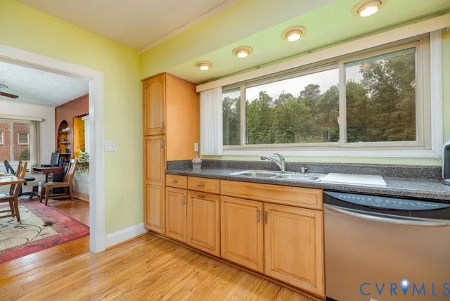 a kitchen with granite countertop a sink and white cabinets with wooden floors