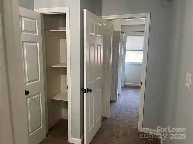 a view of a hallway with wooden floor and closet area