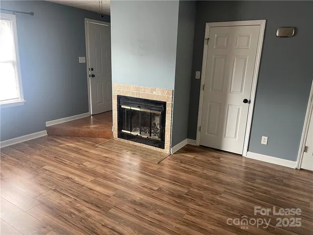 a view of empty room with wooden floor and fireplace