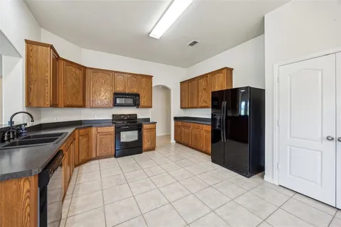 a kitchen with granite countertop a refrigerator and a stove top oven