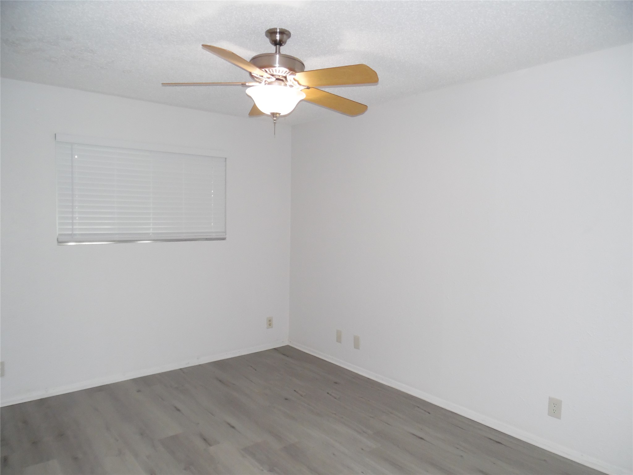 7400 Dixie Drive, Unit B Austin, TX 78744 - Photo 12 of 15 Interior room with light gray wood-finish flooring, white walls, and a ceiling fan with integrated lighting