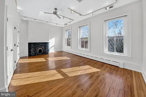 a view of an empty room with wooden floor and a window