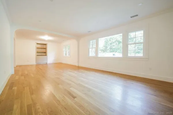 a view of an empty room with wooden floor and a window