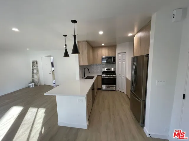 a kitchen with stainless steel appliances granite countertop a refrigerator a sink a stove and a refrigerator with wooden floor