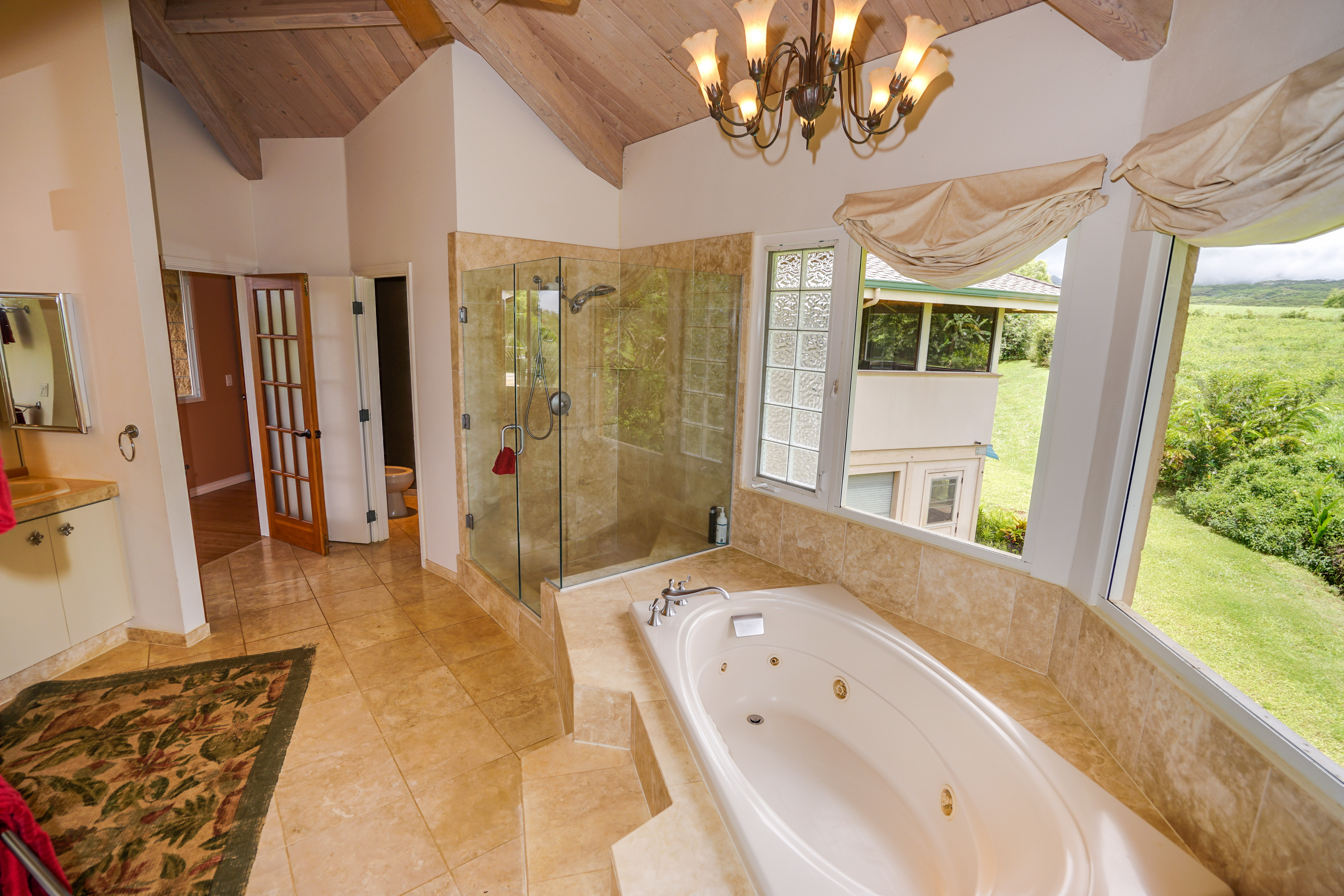 4700 Kapuna Road Kilauea, HI 96754 - Photo 9 of 17 a bathroom with a granite countertop sink a large mirror a bathtub and shower