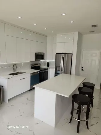 a kitchen with a sink a stove a refrigerator and white cabinets