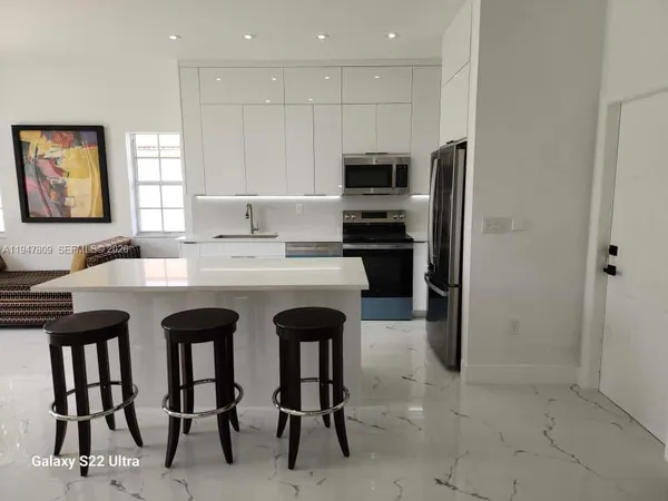 a kitchen with stainless steel appliances kitchen island granite countertop a stove a sink and a refrigerator