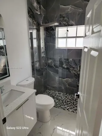 a bathroom with a granite countertop sink a toilet and shower