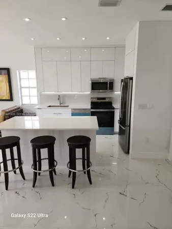 a kitchen with stainless steel appliances a sink a stove a refrigerator with white cabinets and wooden floor