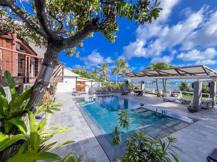 a view of a patio with couches table and chairs under an umbrella with potted plants