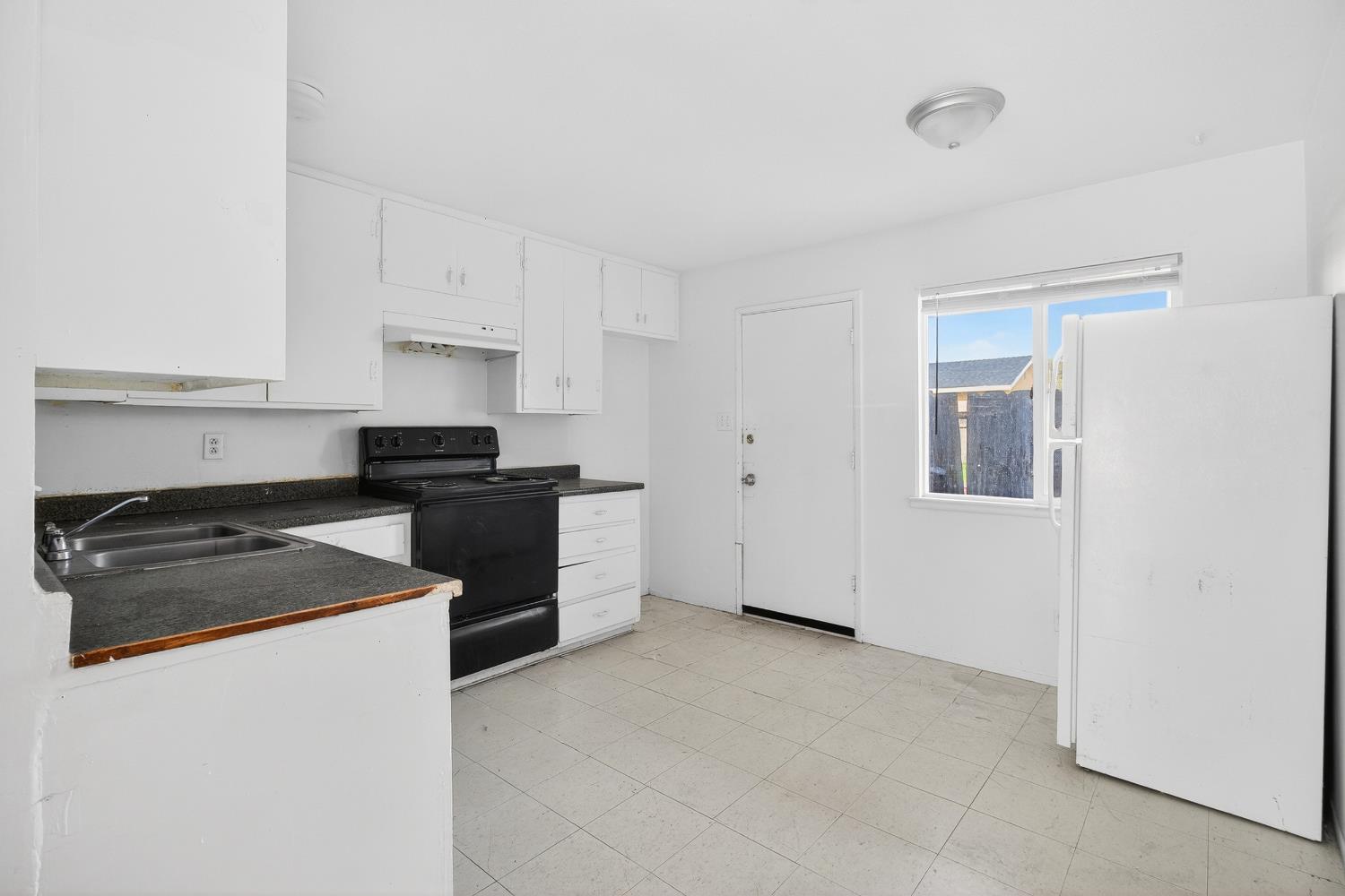 1962 Edwards Avenue Merced, CA 95340 - Photo 16 of 22 a kitchen with granite countertop white cabinets and black appliances
