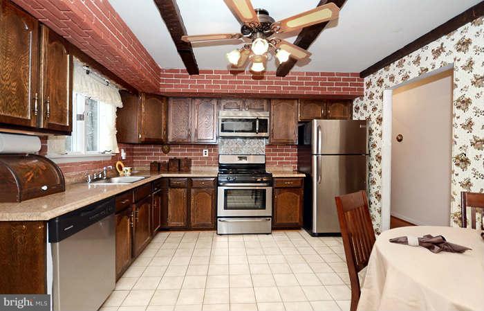 3211 Hunt Road Fallston, MD 21047 - Photo 8 of 25 a kitchen with stainless steel appliances granite countertop a refrigerator a sink dishwasher a stove with wooden cabinets and floor
