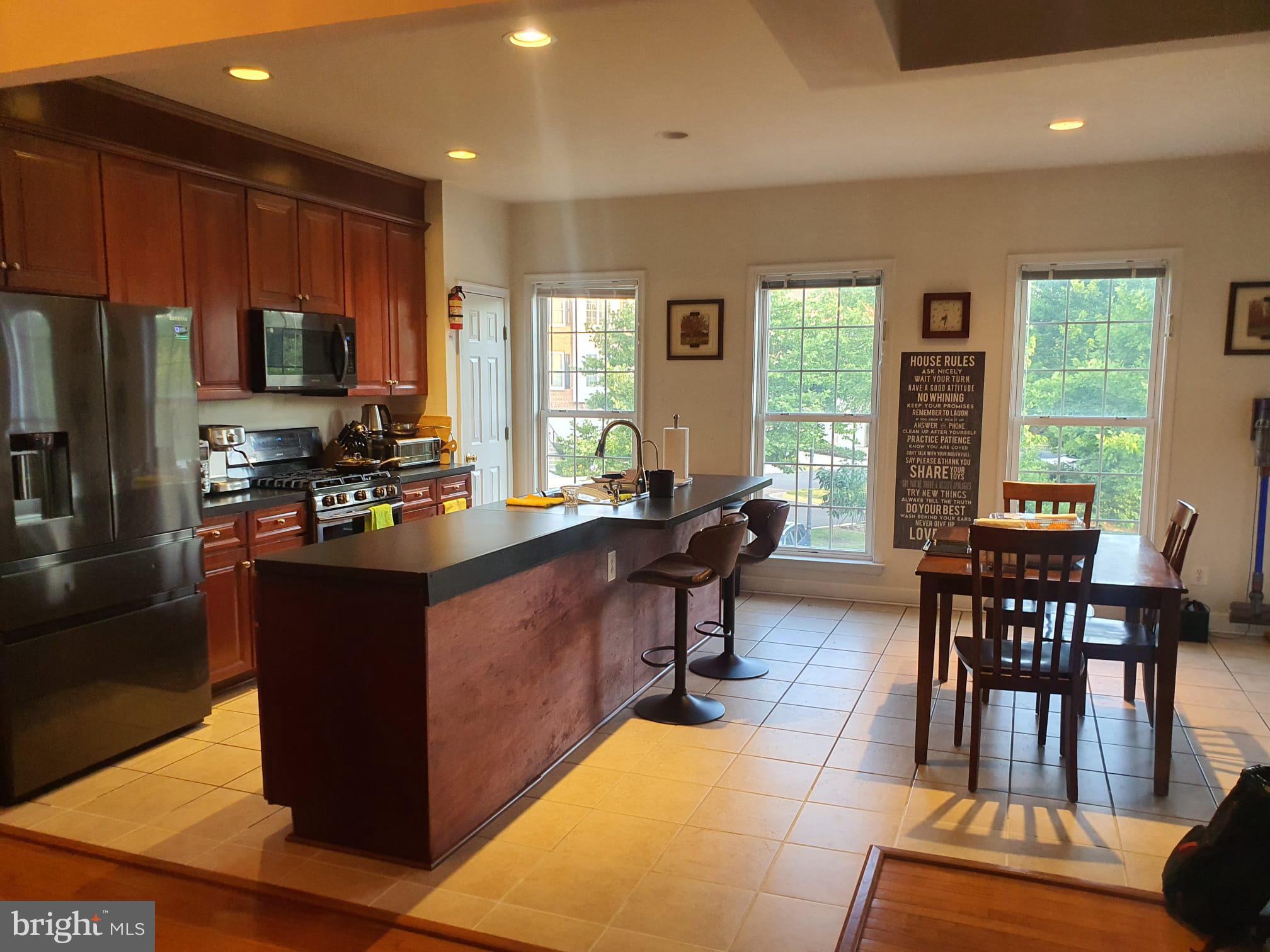 a living room with couches chairs and a flat screen tv with kitchen view