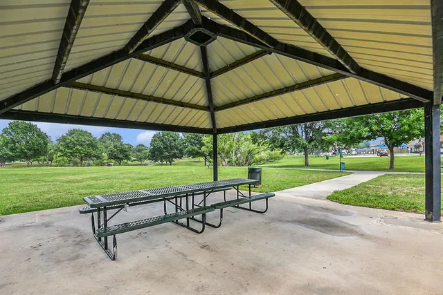 a view of a park with a bench and table under an umbrella