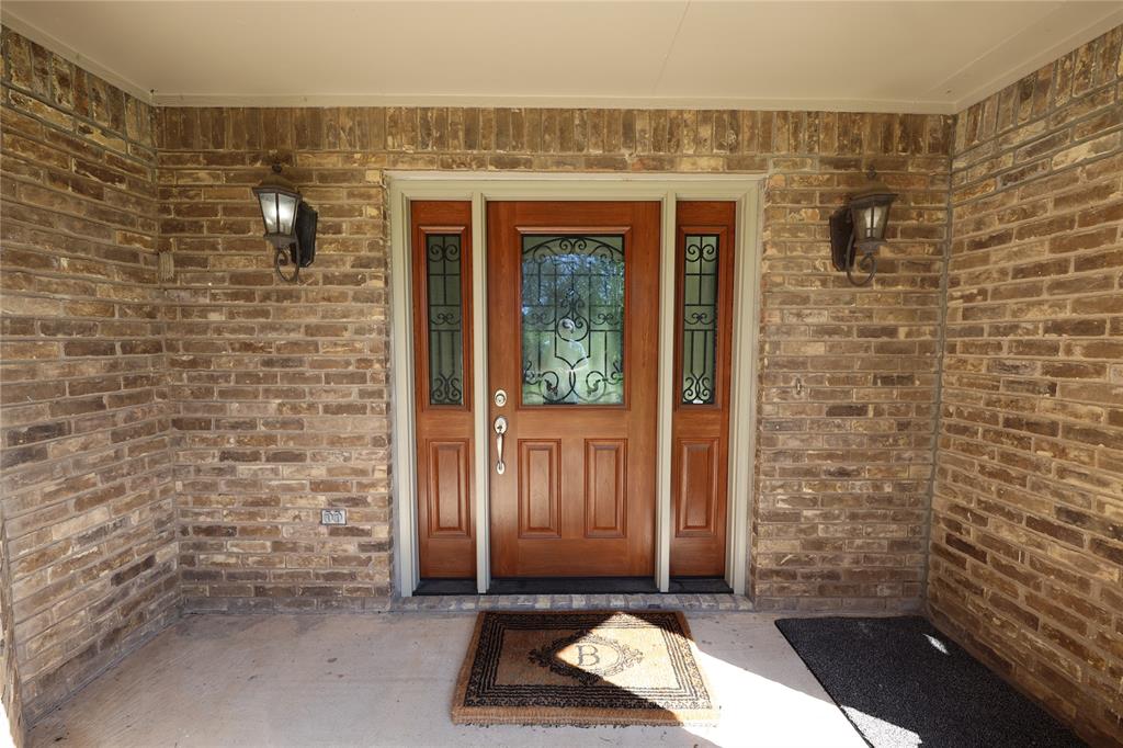 907 Red Oak Creek Road Ovilla, TX 75154 - Photo 4 of 20 Recessed entry featuring a wood-paneled door with decorative glass inserts, flanked by matching sidelights and two exterior sconces