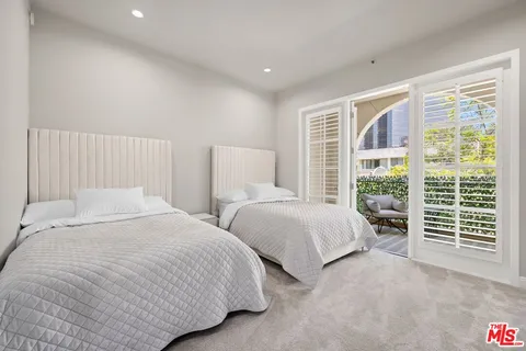 a bedroom with two beds and large windows