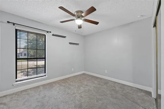 an empty room with windows and ceiling fan