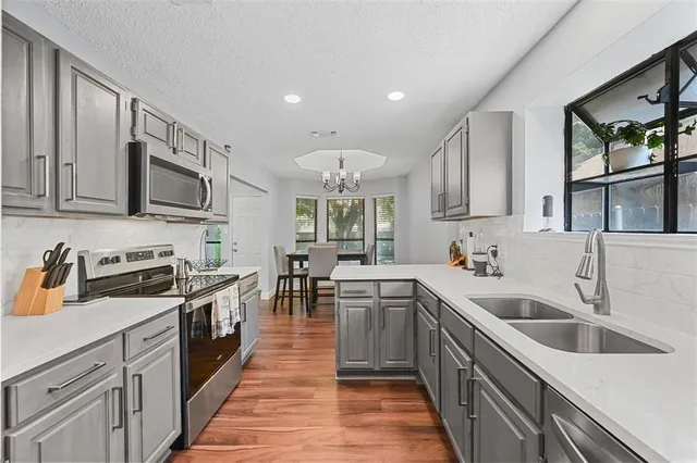 a kitchen with stainless steel appliances granite countertop a sink stove microwave and refrigerator