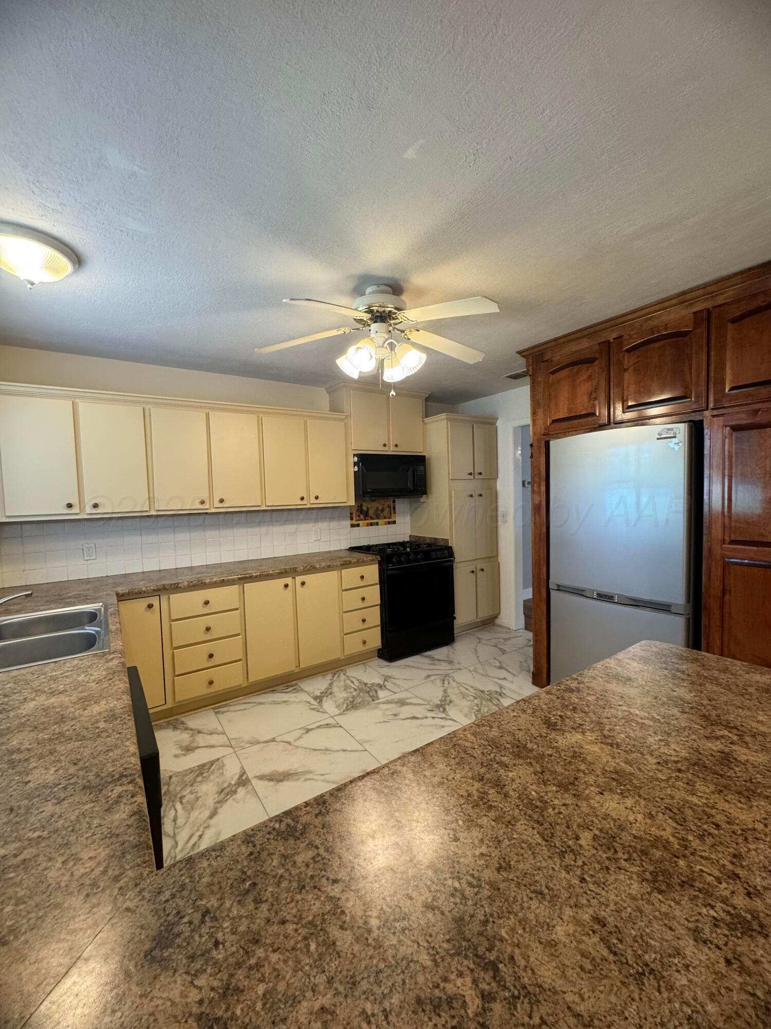 5112 Arden Road Amarillo, TX 79110 - Photo 6 of 28 a kitchen with stainless steel appliances kitchen island granite countertop a refrigerator and a stove top oven