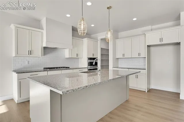 a large kitchen with stainless steel appliances granite countertop a sink a stove a refrigerator and white cabinets