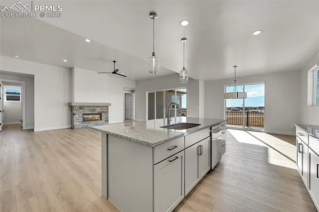 a large kitchen with kitchen island a stove a sink a center island and wooden floor