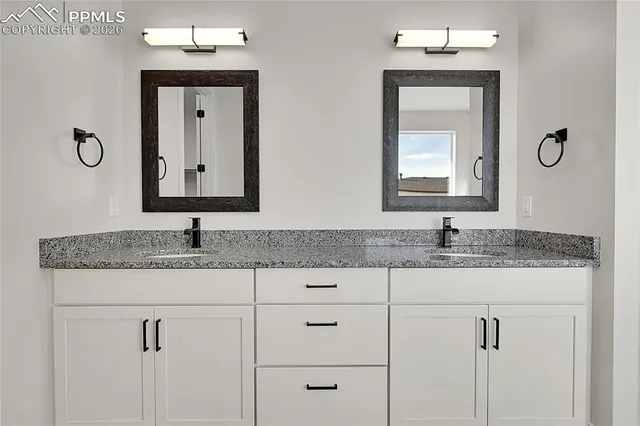 a bathroom with double granite countertop a sink and mirror