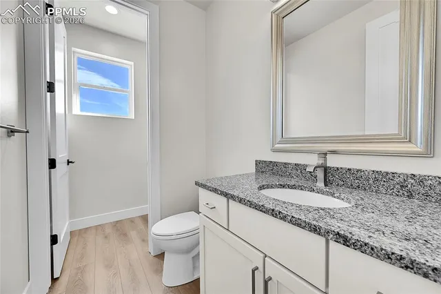 a bathroom with a granite countertop toilet sink and mirror