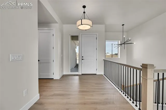 a view of a hallway with wooden floor and a chandelier