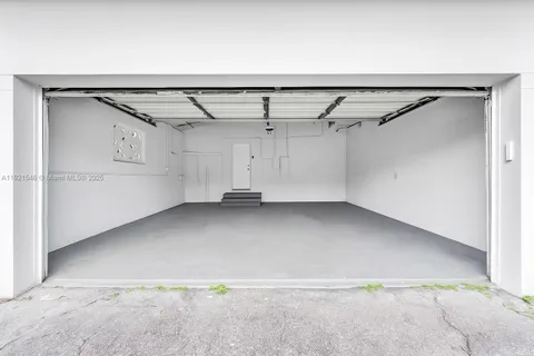 a utility room with stainless steel appliances granite countertop a sink and a refrigerator